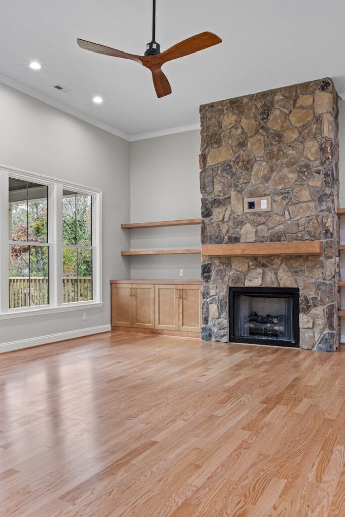 Contemporary living room interior featuring a stone fireplace and wooden flooring.